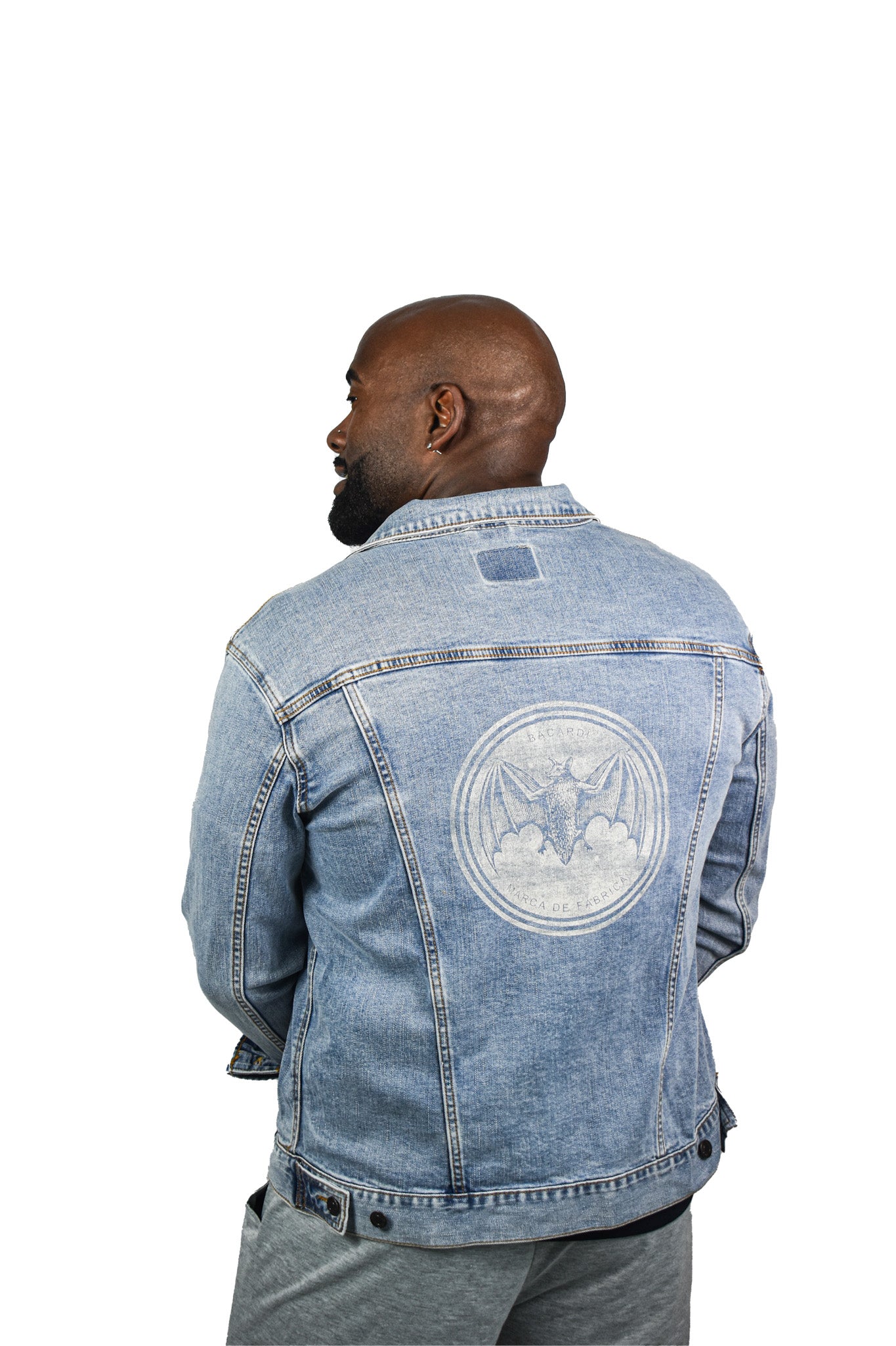 Back view of Bacardi light-wash denim jacket showing large embroidered bat logo, worn by male model.